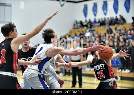 Spieler, der versucht, den Basketball an einem Gegner vorbei zu passieren, nachdem er entlang der Grundlinie und unter dem Korb gefahren ist. USA. Stockfoto