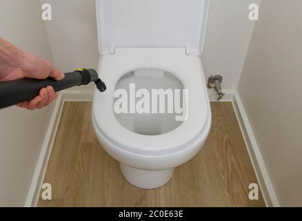 Desinfizieren der Toilettenschüssel mit Dampfreiniger Stockfoto