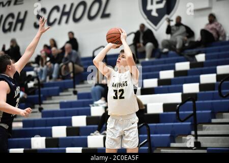 Während weit offen in einer Ecke, ein Spieler setzt einen drei-Punkte-Schuss Versuch über einen spät ankommenden Verteidiger. USA. Stockfoto