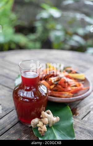 Wedang uwuh Getränke in Glasflaschen und rotem Ingwer, secang rasierte Holz, Zitronengras in Tonteller, ein traditionelles Erbe Javanesen von Indonesien Stockfoto