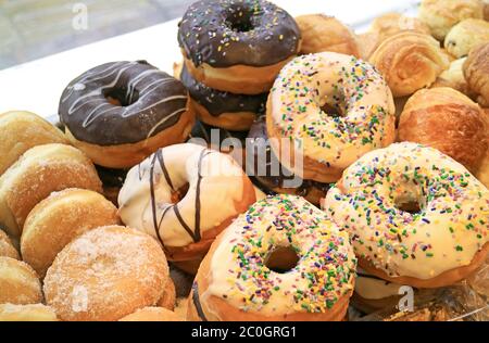 Haufen von verschiedenen Donuts auf dem Regal einer Bäckerei Stockfoto