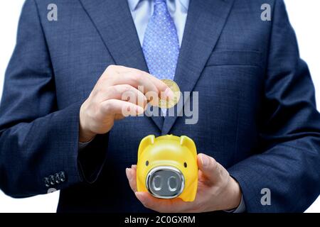 Männliche Geschäftsmann Geld in einem Sparschwein einzahlen. Stockfoto