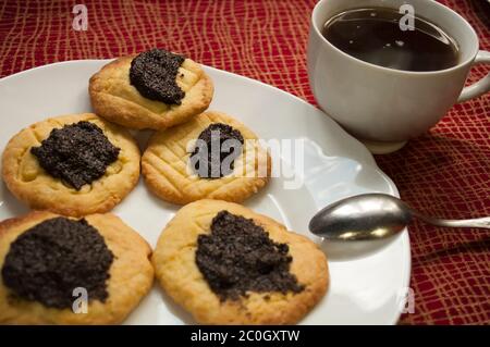 Gebissen Kekse mit Mohnfüllung und Kaffee bei Tageslicht, Backstube Hintergrund, Stockfoto