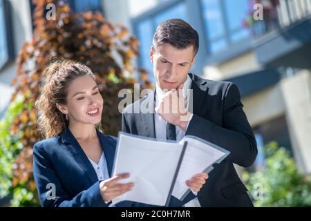 Kunde in einem schwarzen Anzug, der die Vertragsbedingungen überprüft und nachdenklich aussieht Stockfoto