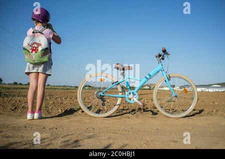 Nettes kleines Mädchen schießen auf dem Land mit ihrem Instant-Bild Fotokamera. Sie hat ein schönes Retro-Fahrrad an der Seite geparkt Stockfoto