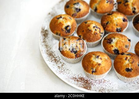 Platte mit frisch gebackenen süßen Muffins. Süße Gebäckstücke, Rezepte, Kochen. Stockfoto