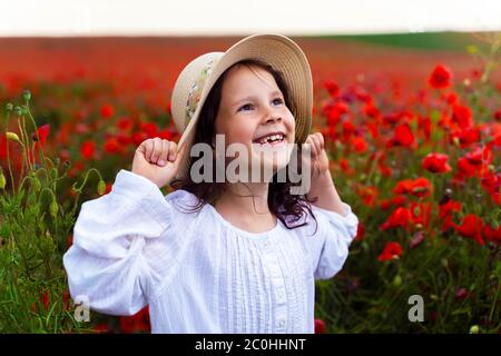 Schönes Mädchen in einem Strohhut in einem Feld mit Mohnblumen. Stockfoto