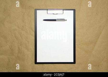 Ein Tablett mit einem weißen Blatt im A4-Format mit Stift auf einem beigen Bastelpapier. Konzept der Analyse, des Studiums, der aufmerksamen Arbeit. Stock Foto mit leerem Platz für Ihren Text und Design. Stockfoto