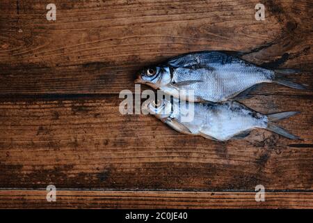 Salziger trockener Flussfisch auf dunklem Holzhintergrund. Trockener Fisch auf dem Markt. Street Food. Bild mit Platz für Text. Stockfoto
