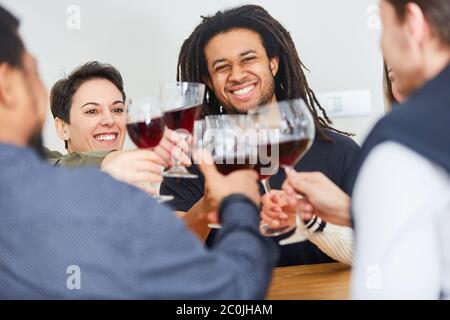 Glückliche Gruppe von Freunden, die zu Hause mit einem Glas Rotwein toasten Stockfoto