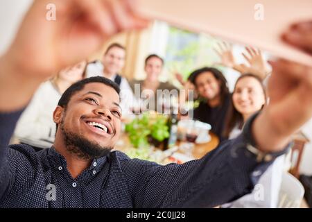 Afrikanischer Mann macht Selfie von Gruppenfreunden beim Essen zusammen als Erinnerung Stockfoto