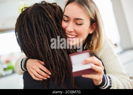 Glückliche Frau umarmt Mann nach Heirat Vorschlag mit Ehering am Valentinstag zu Hause Stockfoto
