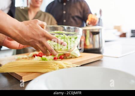 Zubereitung der Hände während des Mittagessens in der Küche mit Salat in Schüssel und Spaghetti Stockfoto