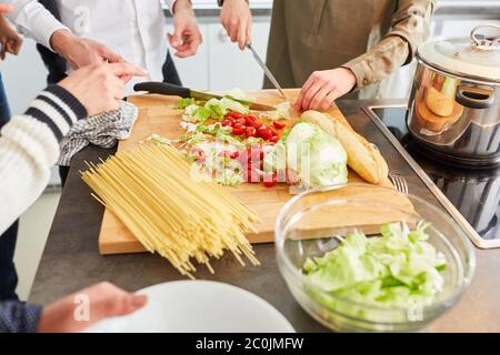 Die Schüler bereiten in der Küche frischen Salat und Pasta für das Mittagessen in einer gemeinsamen Wohnung zu Stockfoto