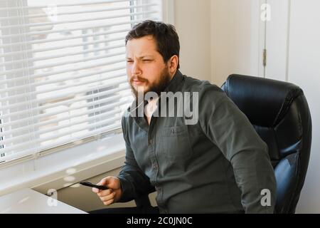 Männlicher Geschäftsleiter, der im Büro archair sitzt und Stift hält. Stockfoto