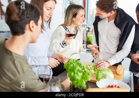 Gruppe von Freunden in der Küche plaudern und bereiten gemeinsam Salat für das Essen zu Stockfoto