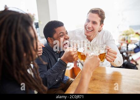 Jubelnde Gruppe von Männern als Freunde Toasting und Bier trinken zusammen Stockfoto