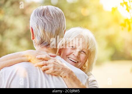 Lachende alte Frau umarmt im Sommer den Mann in der Natur Stockfoto