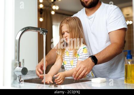 Vater und Tochter waschen sich die Hände über dem Waschbecken in einer Küche Stockfoto