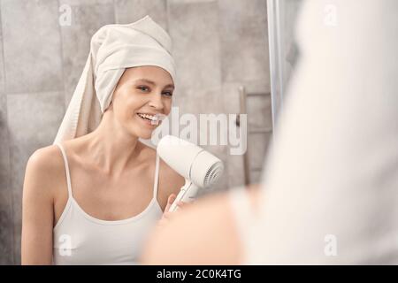 Fröhliche Frau, die einen Fön in der Hand hält Stockfoto