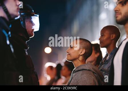 Gruppe von Sozialaktivisten protestieren still vor Polizisten stehen. Frau starrte den Polizisten an und lächelte während einer Kundgebung. Stockfoto