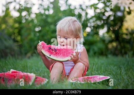 Nettes Kleinkind Kind, Baby Junge, Essen reife Wassermelone im Garten, leckere Früchte Stockfoto