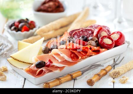 Köstliche Fleischplatte mit Käse, würzigen Oliven und gefülltem Kirschpfeffer als Vorspeise mit Brotstäbchen serviert. Traditionelle spanische Tapas mit ha Stockfoto