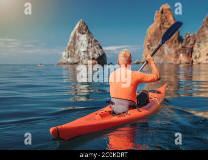 Kajak. Sportler Kajakmann genießt Abenteuer auf ruhigen Meer mit blauem Wasser. Freizeitaktivitäten auf dem ruhigen blauen Wasser. Das Konzept eines aktiven und gesunden Stockfoto