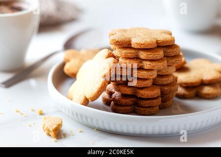 Frisch gebackene hausgemachte Kekse zum Frühstück mit einer Tasse Kaffee im Hintergrund. Konzept „Guten Morgen“