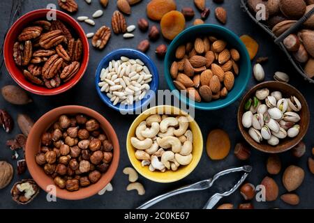 Verschiedene Arten von Nüssen - Mandeln, Pinienkerne, Pastachio, Cashew, Pecan und Haselnüsse - in Schalen. Ansicht von oben Stockfoto