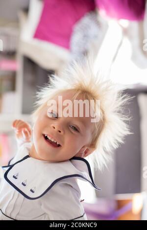 Lustige zwei Jahre altes Kind, Junge, hängend auf dem Kopf, lächelnd glücklich, Mutter hält ihn Stockfoto