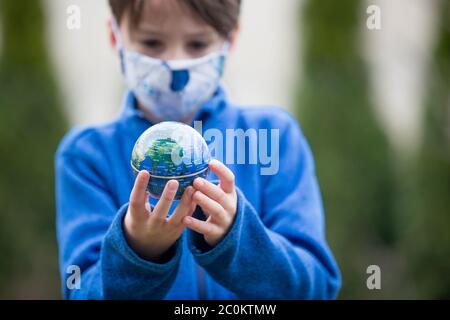 Schulkind, hält kleine Kugel, Blick traurig auf die Welt während Covid 19 Pandemie, Virus, das sich weltweit verbreitet Stockfoto