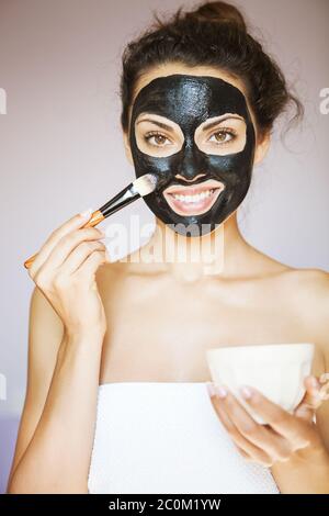 Junge schöne Frau, die Anwendung einer Maske für das Gesicht der schwarzen Heilschlamm Stockfoto