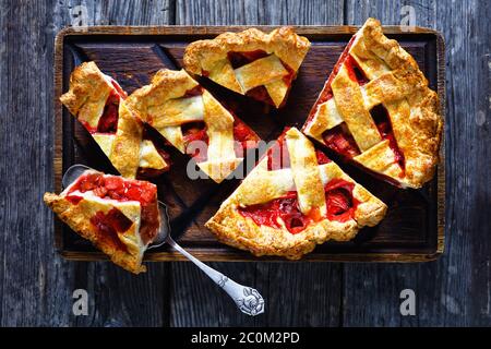 Hausgemachte Erdbeer Rhabarb Pie Scheiben auf einem Schneidebrett auf einem Holztisch, flach legen, freien Raum Stockfoto