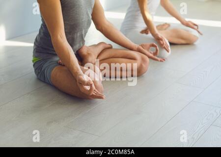 Nahaufnahme des Yoga-Ehepaares die Menschen geben sich in der Studioklasse Entspannung im lotus-feld auf dem Boden. Stockfoto