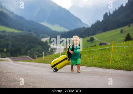 Kleine Kinder, Junge Brüder mit Rucksäcken und Koffer, reisen auf der Straße zu malerischen Bergen Stockfoto