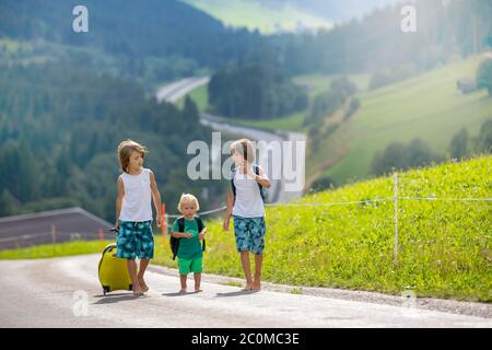 Kleine Kinder, Junge Brüder mit Rucksäcken und Koffer, Reisen auf der Straße zu malerischen Bergen, , Sommerzeit Stockfoto