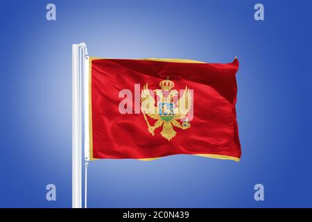Flagge Montenegros, die gegen einen blauen Himmel fliegt Stockfoto