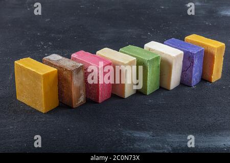 Viele verschiedene handgemachte Seifenstücke auf schwarzem Holz Hintergrund. Verschiedene handgemachte Seifenstücke, flach liegend, Draufsicht. Öko Seife und Kosmetik. Natürlich gesund Stockfoto