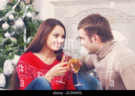 Junges glückliches Paar, das Champagner am Christmasbaum trinkt Stockfoto