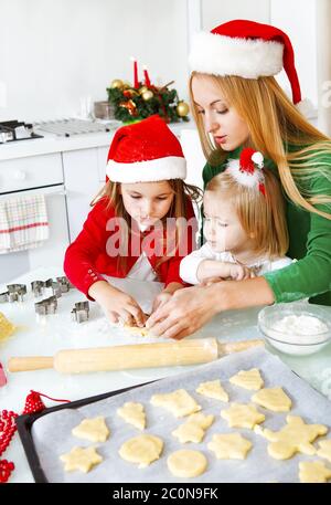 Zwei liebenswerte Mädchen und Mutter backen Weihnachtskekse Stockfoto