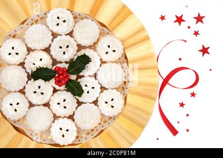 Traditionelle Weihnachtskuchen auf einem Goldteller mit Stechpalme auf weißem Hintergrund mit roten Sternen und Band. Hausgemachte Weihnachten Essen Zusammensetzung. Stockfoto