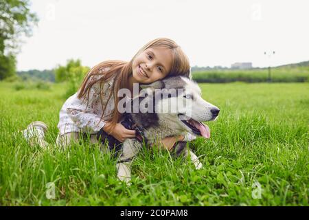 Teen Mädchen umarmt ihren Husky Hund an einem Tag auf einer Wiese in der Natur. Stockfoto