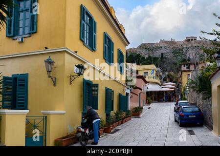 Athen, Attika / Griechenland. Malerischer Blick auf das Plaka-Viertel in Athen unter dem berühmten Akropolis-Felsen. Schmale gepflasterter Gasse, traditionelle Gebäude Stockfoto