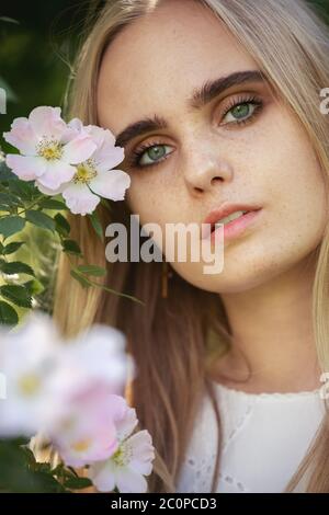 Glücklich ziemlich blonde Mädchen mit Blumen Blick auf die Kamera Stockfoto