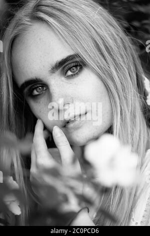 Glücklich ziemlich blonde Mädchen mit Blumen Blick auf Kamera, monochrom Stockfoto