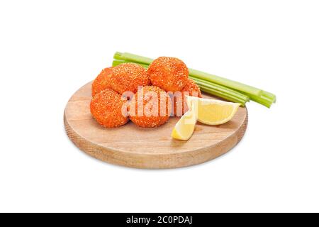 Rohe knusprige Hühnchen-Nuggets paniert in gemahlenem Chili-Pfeffer und Semmelbröseln auf einem Holzbrett mit Sellerie-Sticks und Zitrone. Bereit zum Braten. Frisch paniert Stockfoto