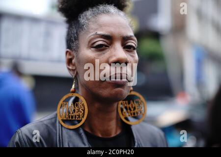 Eine Frau mit Ohrringen, die sagen, dass Schwarz lebt Materie bei der Enthüllung einer BLM-Plakatwand Westminster Bridge Road, London. Stockfoto