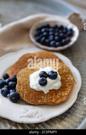 Vertikale Bild der Haferflocken Pfannkuchen mit Joghurt und Heidelbeeren gekrönt. Geringe Schärfentiefe. Stockfoto