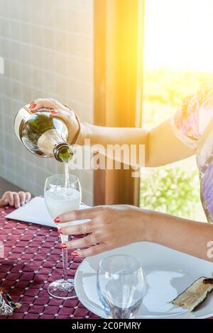 Die Hand der Frau gießt Wein in ein Glas. Feiern mit Freunden. Gießt Apfelwein in ein Glas. Stockfoto